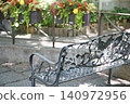 A garden in the shade with red flowers and an old bench. 140972956