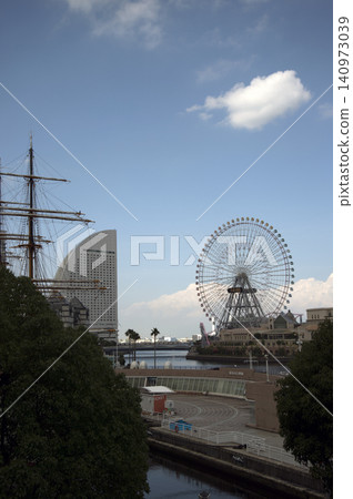 A Ferris wheel and Yokohama Port Museum against a blue sky. A Ferris wheel and Yokohama Port Museum against a blue sky. 140973039