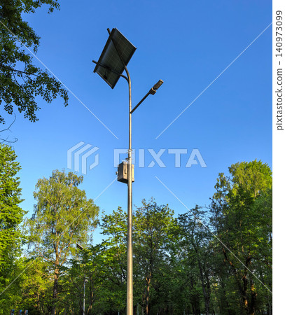 Solar powered street lamp post with panel in green park against blue sky Solar powered street lamp post with panel in green park against blue sky 140973099