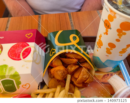 Fast food meal with burger box potato wedges fries and drink cup on tray Fast food meal with burger box potato wedges fries and drink cup on tray 140973125