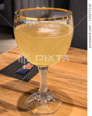 Tall stemmed beer glass with golden ale on wooden restaurant table closeup Tall stemmed beer glass with golden ale on wooden restaurant table closeup 140973126