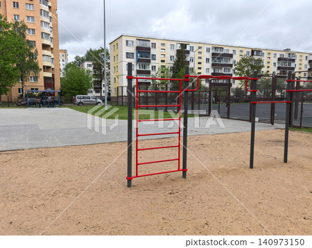 Red workout bars on sand playground near residential apartment buildings Red workout bars on sand playground near residential apartment buildings 140973150