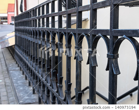 Black wrought iron fence with decorative arches in urban setting Black wrought iron fence with decorative arches in urban setting 140973194