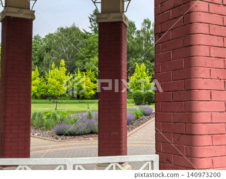 View through red brick gazebo columns to a green summer park View through red brick gazebo columns to a green summer park 140973200