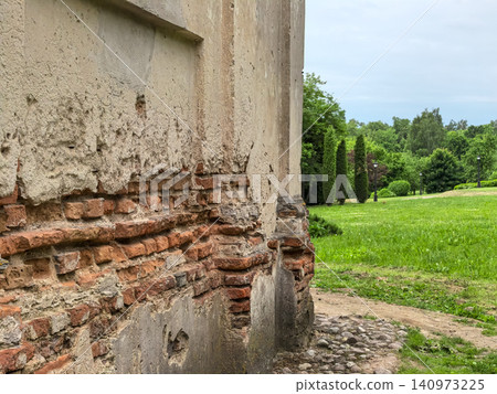 Old historic brick wall ruin with damaged plaster in green park landscape Old historic brick wall ruin with damaged plaster in green park landscape 140973225