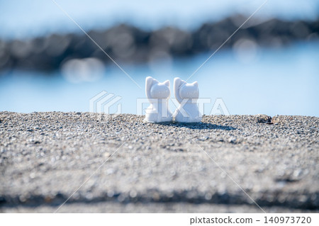 A figurine of a cat gazing at the sea and sky - an image of a cat watching over the ocean. A figurine of a cat gazing at the sea and sky - an image of a cat watching over the ocean. 140973720