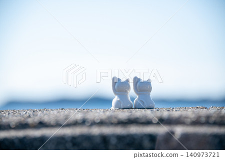 A figurine of a cat gazing at the sea and sky - an image of a cat watching over the ocean. 140973721