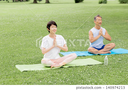 An active senior couple enjoying meditation yoga in the park An active senior couple enjoying meditation yoga in the park 140974213