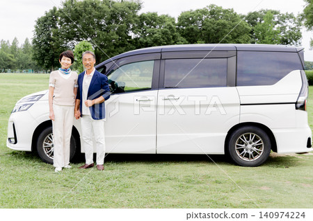 An active senior couple smiles in front of a minivan. An active senior couple smiles in front of a minivan. 140974224