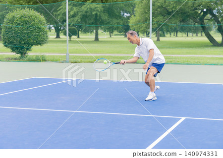 Senior men hitting shots on an outdoor tennis court. Senior men hitting shots on an outdoor tennis court. 140974331