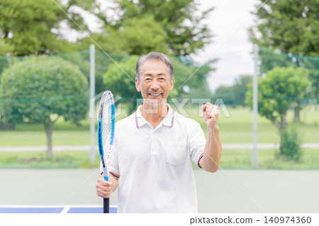 一位面帶微笑的資深網球選手擺出勝利姿勢。 一位面帶微笑的資深網球選手擺出勝利姿勢。 140974360