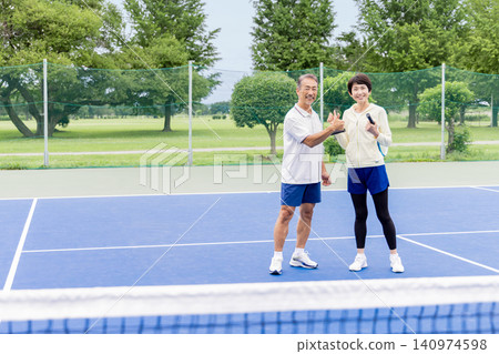 A senior couple enjoying tennis and congratulating each other on their efforts with smiles on their faces. A senior couple enjoying tennis and congratulating each other on their efforts with smiles on their faces. 140974598