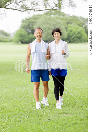 A smiling senior couple enjoying a walk in the park. A smiling senior couple enjoying a walk in the park. 140974613