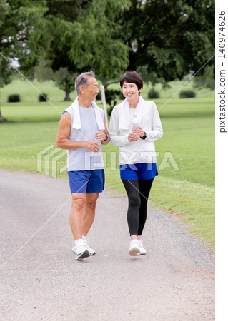 A smiling, active senior couple enjoying a walk and staying hydrated. A smiling, active senior couple enjoying a walk and staying hydrated. 140974626
