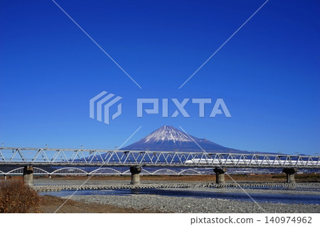 A Shinkansen train crossing the Fujikawa Railway Bridge with Mount Fuji in the background. January, Mount Fuji 2054 Shinkansen and Fujikawa Railway Bridge 140974962