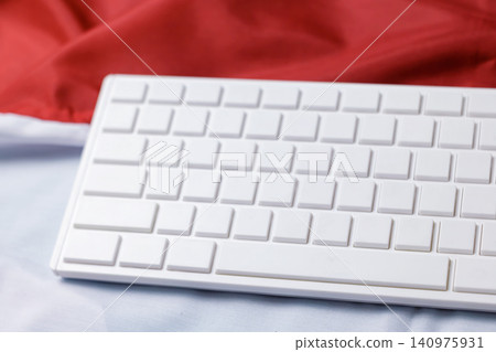 An angled shot of a white computer keyboard without letters resting on an Indonesian or Polish flag backdrop. High Quality Photo An angled shot of a white computer keyboard without letters resting on an Indonesian or Polish flag backdrop. High Quality Photo 140975931