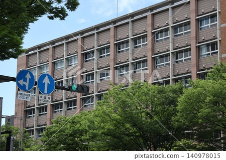 街景：藍天、藍色交通燈、路牌、街道兩旁綠樹成蔭，還有一棟學校建築。 140978015