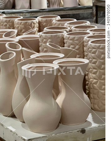 Several handcrafted ceramic vases in different designs await firing in a pottery studio, highlighting the artistry of clay shaping Several handcrafted ceramic vases in different designs await firing in a pottery studio, highlighting the artistry of clay shaping 140978050