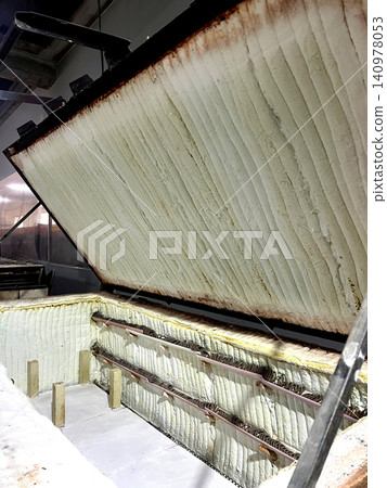 A ceramic kiln open, showcasing the inner chamber lined with insulation, ready for firing clay pottery in a workshop setting A ceramic kiln open, showcasing the inner chamber lined with insulation, ready for firing clay pottery in a workshop setting 140978053
