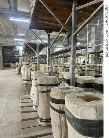 Workers create and store various ceramic pieces made from clay in a large production facility during daylight hours Workers create and store various ceramic pieces made from clay in a large production facility during daylight hours 140978067