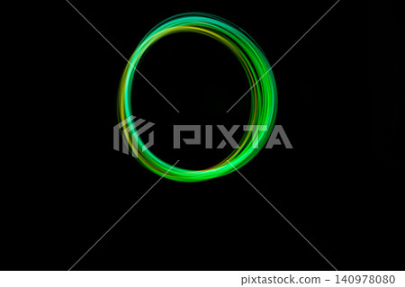 A vibrant green light circle emerges, showcasing freeze light artistry in a dark environment during night hours A vibrant green light circle emerges, showcasing freeze light artistry in a dark environment during night hours 140978080