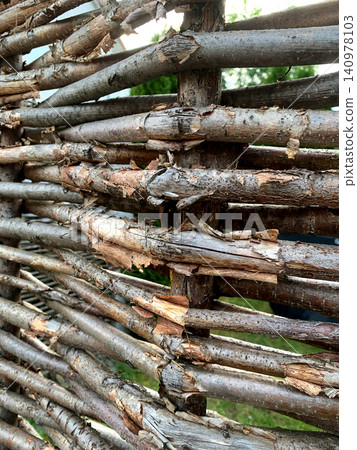 Weathered wooden fence displays rough textures and age, surrounded by greenery and natural light in a peaceful setting Weathered wooden fence displays rough textures and age, surrounded by greenery and natural light in a peaceful setting 140978103
