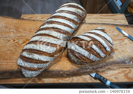 Striped Sourdough Loaves on Board With Knife and Flour 140978159