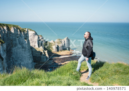 Man stands and look at cliffs and Waters of Etretat Man stands and look at cliffs and Waters of Etretat 140978571