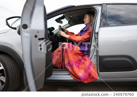 Driver woman with blonde hair sits in car moving gear ready to start driving. Horizontal. Driver woman with blonde hair sits in car moving gear ready to start driving. Horizontal. 140979760