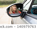 Driver woman in car mirror reflection observing surroundings during daylight. Horizontal. Selective focus. 140979763
