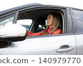 driver sitting in car looking ahead in parking lot during daytime. Activity happens during daytime. Horizontal. 140979770