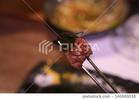 Grilled Meat with Leaf on Tongs Close-up Grilled Meat with Leaf on Tongs Close-up 140980038