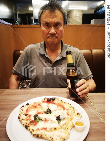 一個男人一邊喝啤酒一邊吃披薩 一個男人一邊喝啤酒一邊吃披薩 140981394