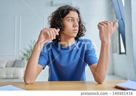 Serious teen boy listening during online lesson Serious teen boy listening during online lesson 140981416