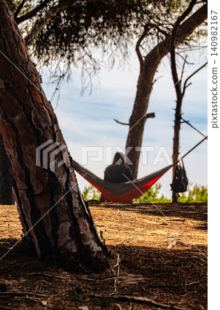 Adult spends a day at the beach with scenic views seated in a hammock Adult spends a day at the beach with scenic views seated in a hammock 140982167