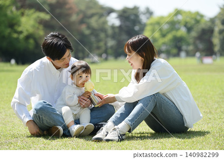 A young couple gives their daughter water from a thermos. A young couple gives their daughter water from a thermos. 140982299