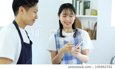 Kitchen: Image of a man and woman thinking up recipes on their smartphones. Kitchen: Image of a man and woman thinking up recipes on their smartphones. 140982592