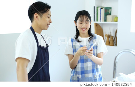 Kitchen: Image of a man and woman thinking up recipes on their smartphones. Kitchen: Image of a man and woman thinking up recipes on their smartphones. 140982594