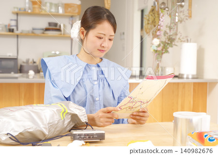 一名女子正在檢查災害地圖和災害防備物資。 一名女子正在檢查災害地圖和災害防備物資。 140982676
