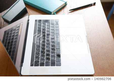 A laptop and a notebook placed on the desk. A laptop and a notebook placed on the desk. 140982706