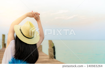 Rear view a young woman stretching on a wooden pier. Wellness, relaxation, tropical travel, vacation, mindfulness, freedom. Healthy living, travel, vacation, tropical beach escape, personal wellbeing. Rear view a young woman stretching on a wooden pier. Wellness, relaxation, tropical travel, vacation, mindfulness, freedom. Healthy living, travel, vacation, tropical beach escape, personal wellbeing. 140983264