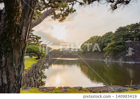 The Imperial Palace, pine trees, and pond are beautifully illuminated by the sun. The Imperial Palace, pine trees, and pond are beautifully illuminated by the sun. 140983419