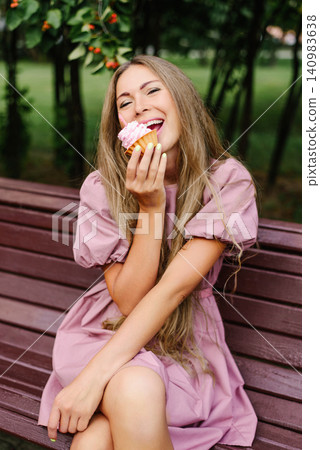 Woman Sitting In Park With Cupcake Woman Sitting In Park With Cupcake 140983638