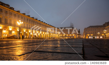 Turin, piedmont, italy. November 20, 2024. Piazza san carlo showing illuminated historic buildings, arcades, and a statue during a moody, foggy early morning in turin Turin, piedmont, italy. November 20, 2024. Piazza san carlo showing illuminated historic buildings, arcades, and a statue during a moody, foggy early morning in turin 140983689