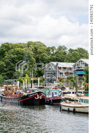 A small boat moored on the Thames River surrounded by greenery, near Eel Pie Island, outside London. A small boat moored on the Thames River surrounded by greenery, near Eel Pie Island, outside London. 140983791