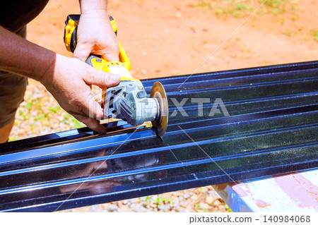 Handyman uses cutting tool on metal sheet in yard sparks fly as tool makes cutting contact Handyman uses cutting tool on metal sheet in yard sparks fly as tool makes cutting contact 140984068