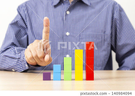 A man pointing at a graph made of building blocks. A man pointing at a graph made of building blocks. 140984094