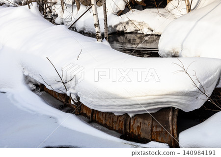 snow-covered pipes in puddle of melted snow snow-covered pipes in puddle of melted snow 140984191