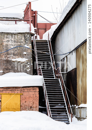 snow-covered stairs in courtyard of idle factory 140984275