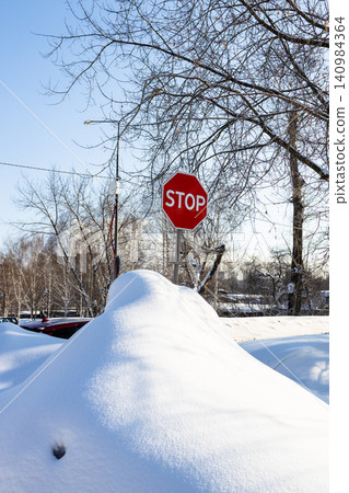 STOP sign in snowdrift on side of city road STOP sign in snowdrift on side of city road 140984364